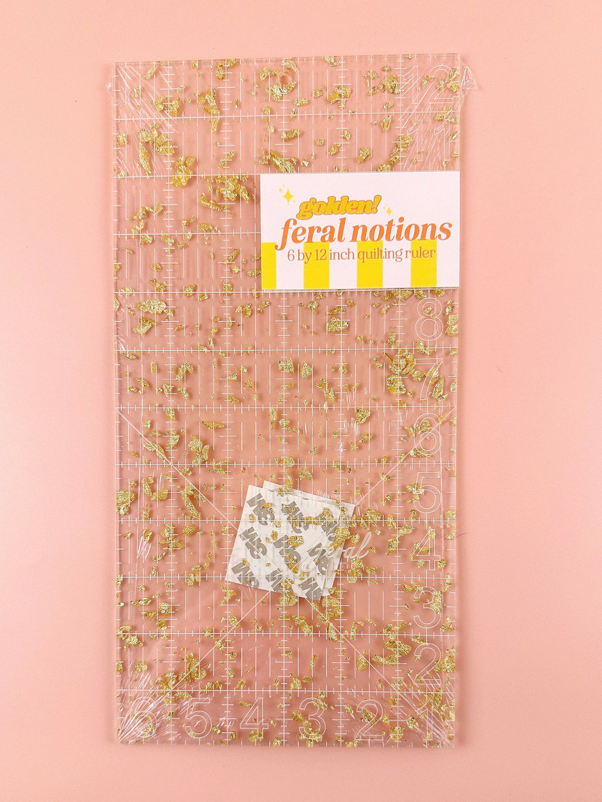 Feral Notions 6 x 12 inch quilting ruler in gold glitter acrylic with its paper label