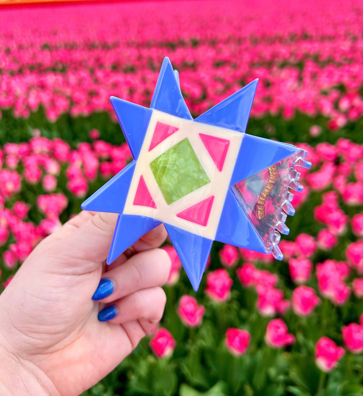The Peach Fuzz quilt hair claw with a quilt block design held in a tulip field
