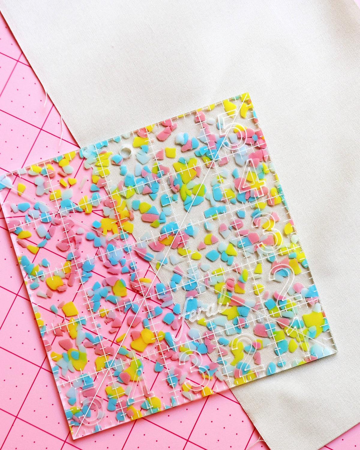 Feral Notions 5 inch charm square quilting ruler in confetti acrylic on white fabric for cutting 5 inch charm squares