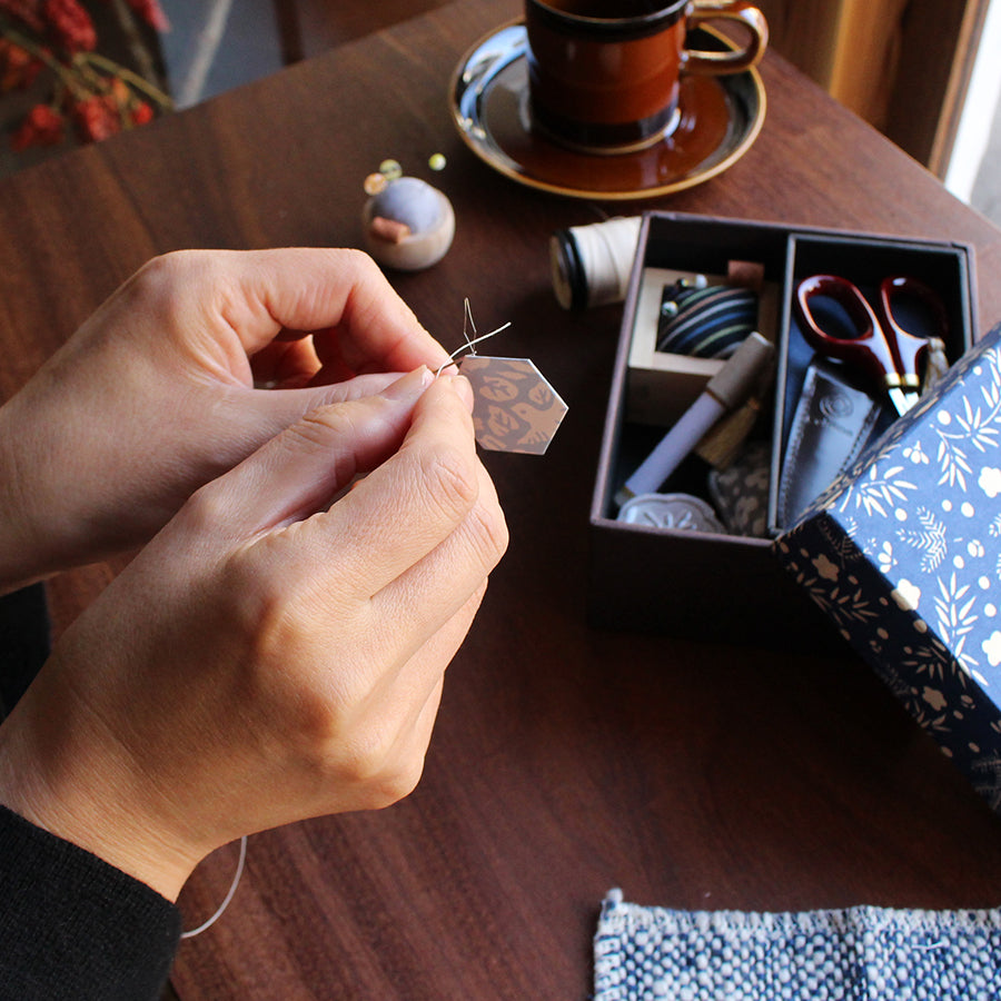 Cohana Haibara chiyogami needle threader, in use at a sewing table