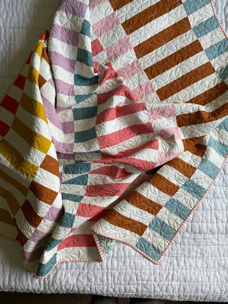 Close-up of the Penelope Handmade Madeline quilt pattern quilt folded to show the pieced bars and binding
