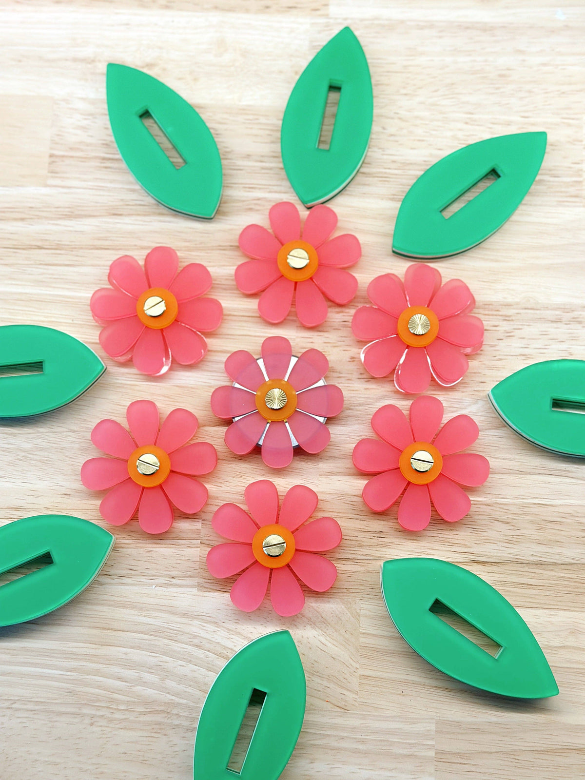 Feral Notions flower thread cutters arranged in a ring with green leaves, sewing notions