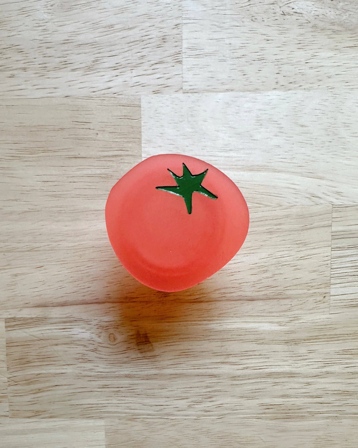 Feral Notions tomato pop-up ruler handle, a red quilting ruler grip, on wood
