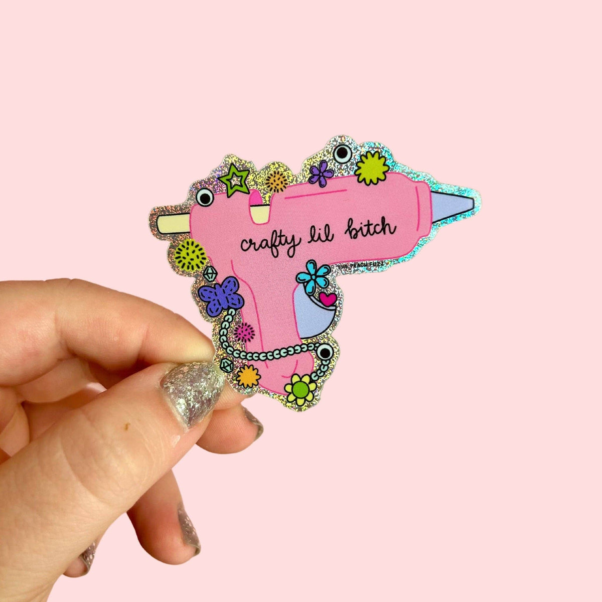 The Peach Fuzz Crafty Lil Bitch hot glue gun glitter sticker held in hand