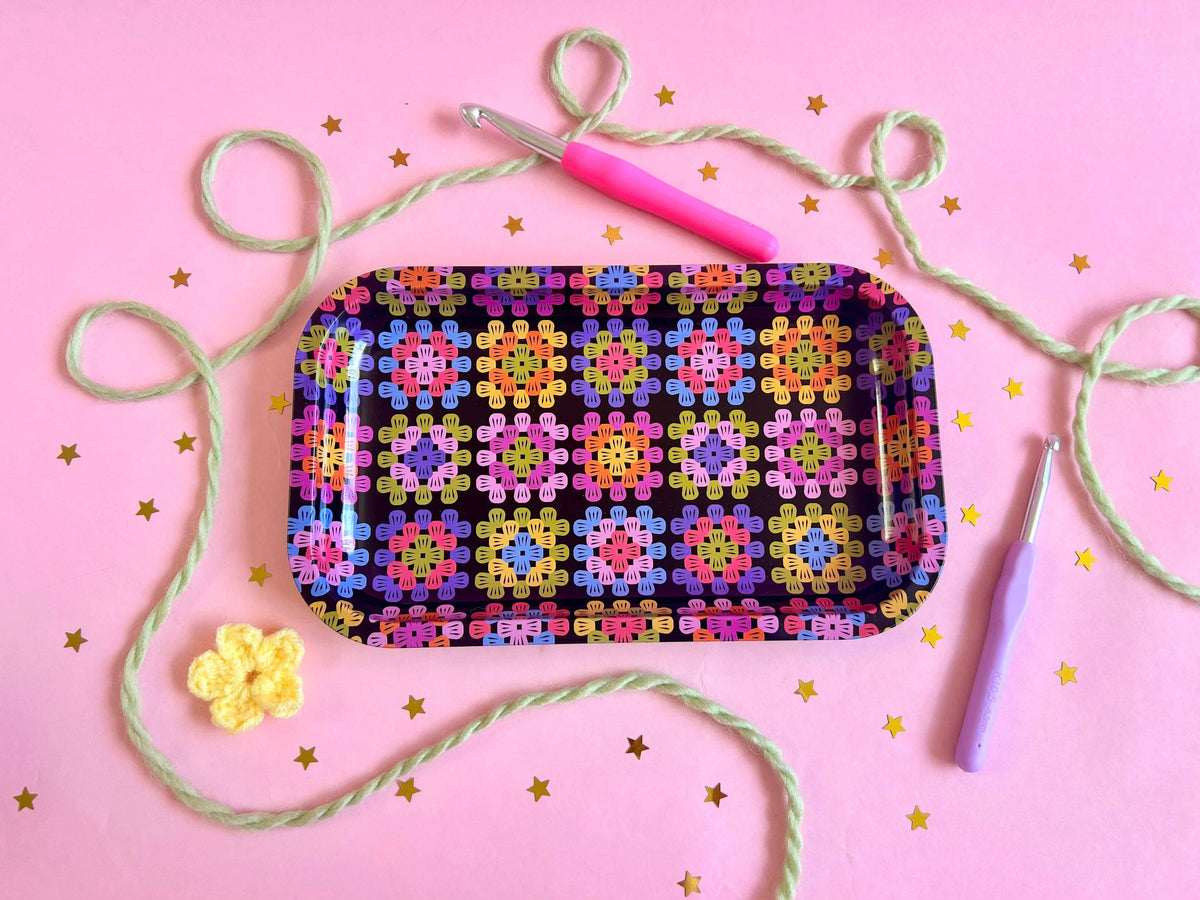 The Peach Fuzz large granny square tray with knitting supplies on pink