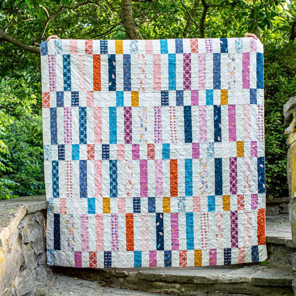 Finished quilt made with the Penelope Handmade Madeline quilt pattern hanging outdoors
