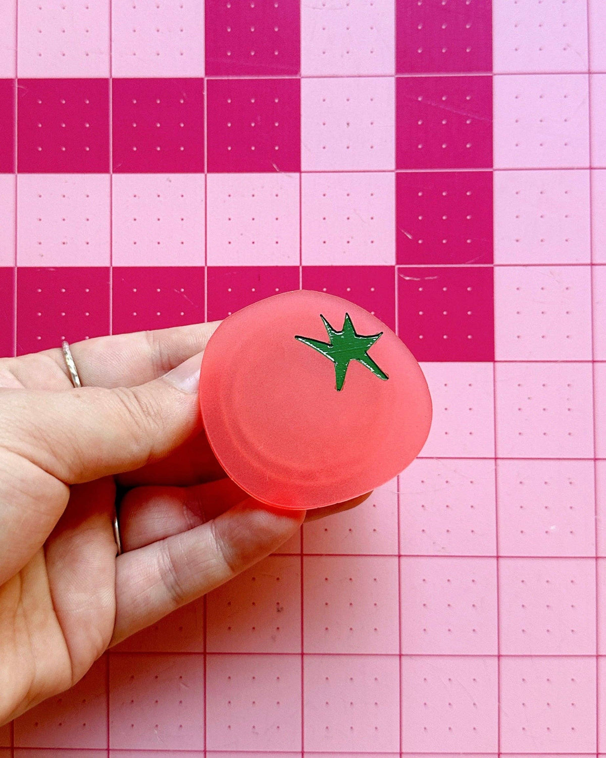 Hand gripping the Feral Notions tomato pop-up ruler handle on a cutting mat