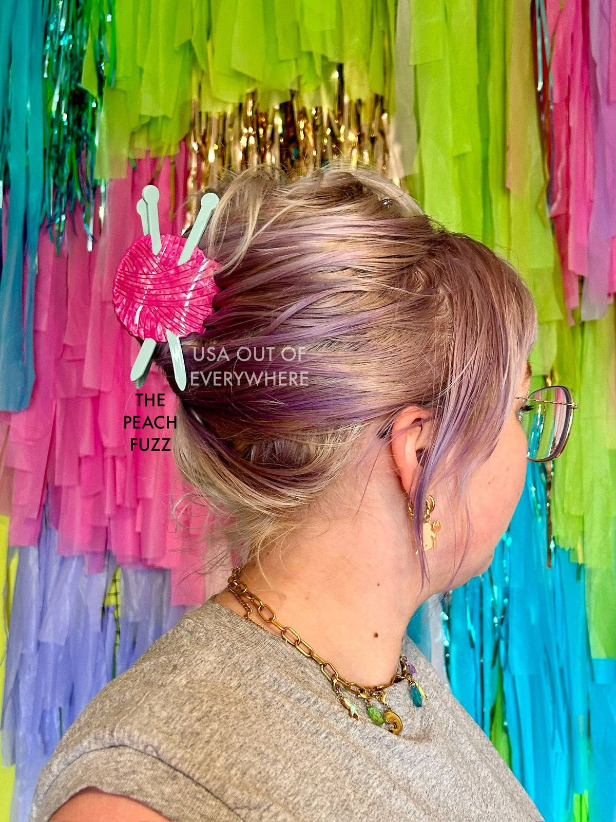 The Peach Fuzz knitting needle hair claw in pink worn in hair against rainbow fringe