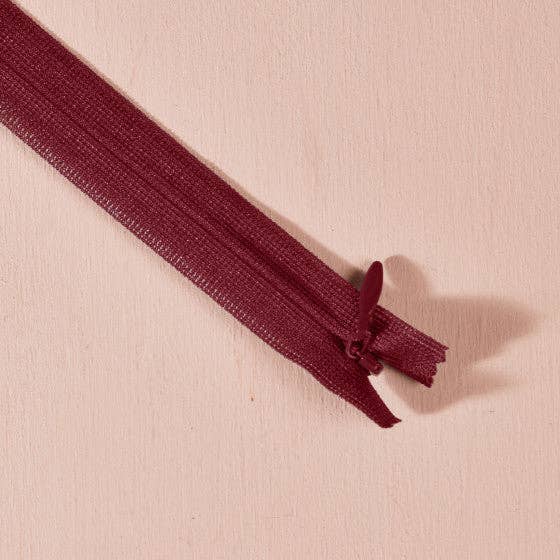 Atelier Brunette invisible zipper in wine burgundy, 40 cm (16 inch), a dressmaking notion for dresses and skirts shown on a blush background