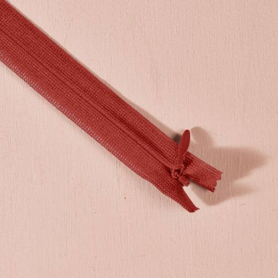 Atelier Brunette invisible zipper in brick red terracotta, 40 cm (16 inch), a dressmaking notion for dresses and skirts shown on a blush background