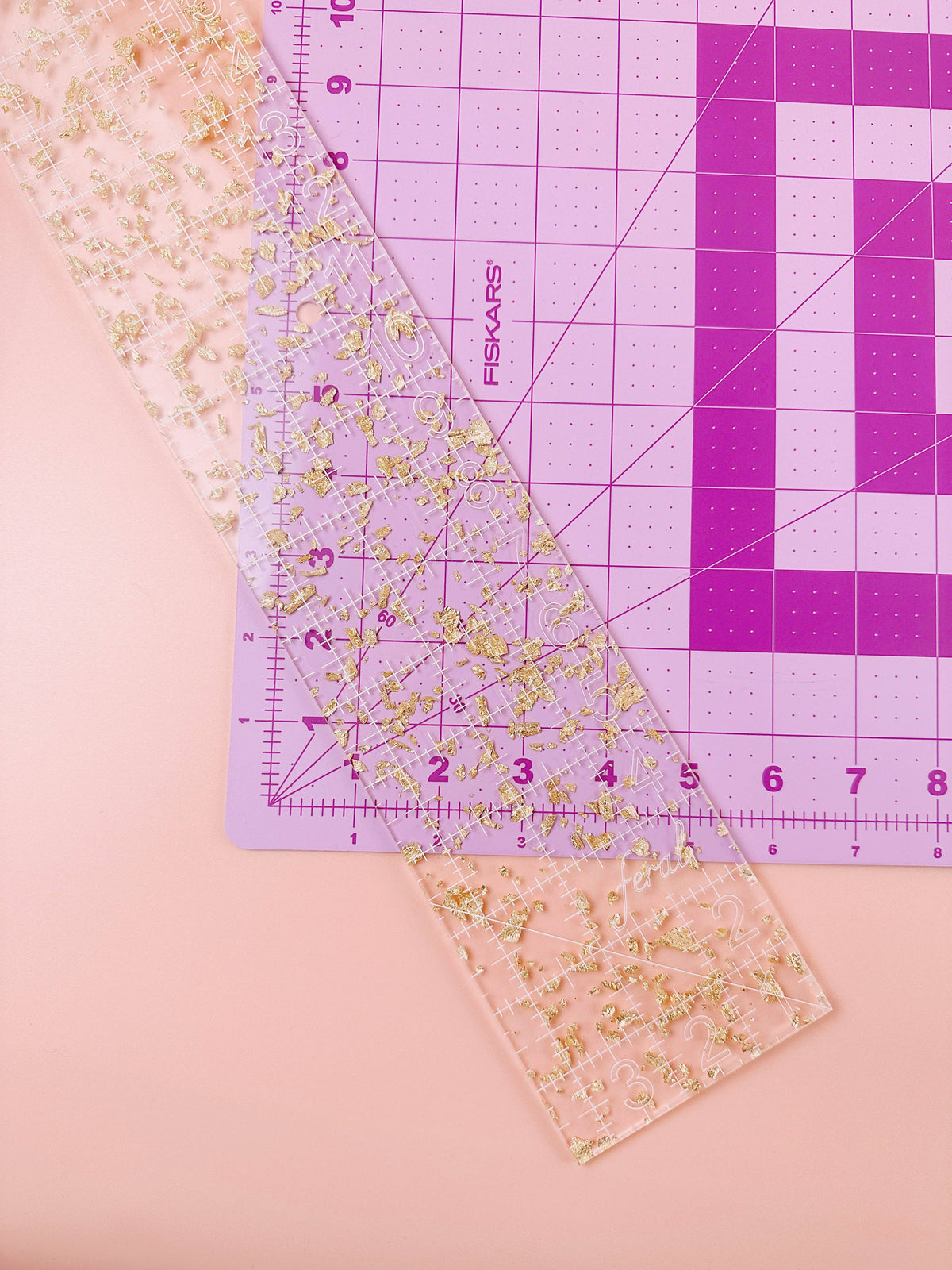 Feral Notions fat quarter quilting ruler in gold glitter acrylic on a lilac cutting mat for cutting fat quarters