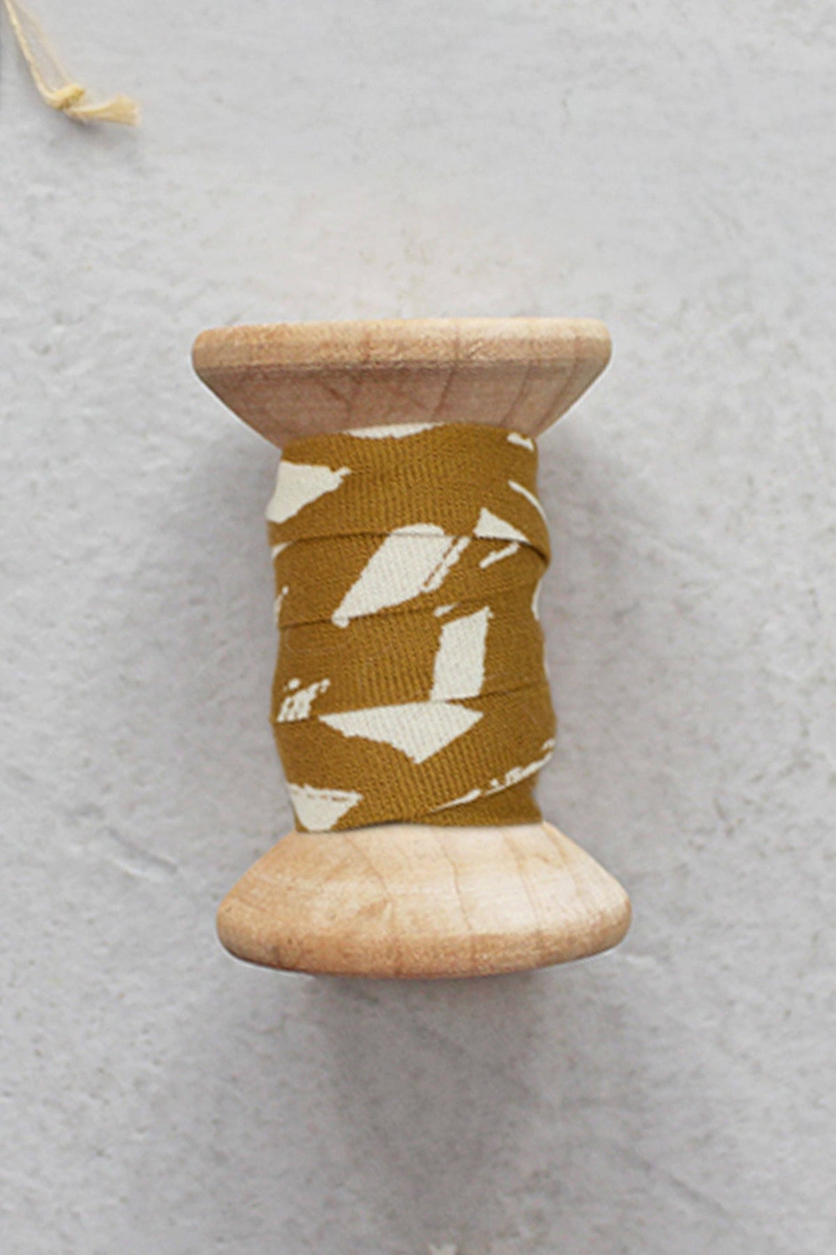 Atelier Brunette bias tape in ochre on a wooden spool, cotton bias binding