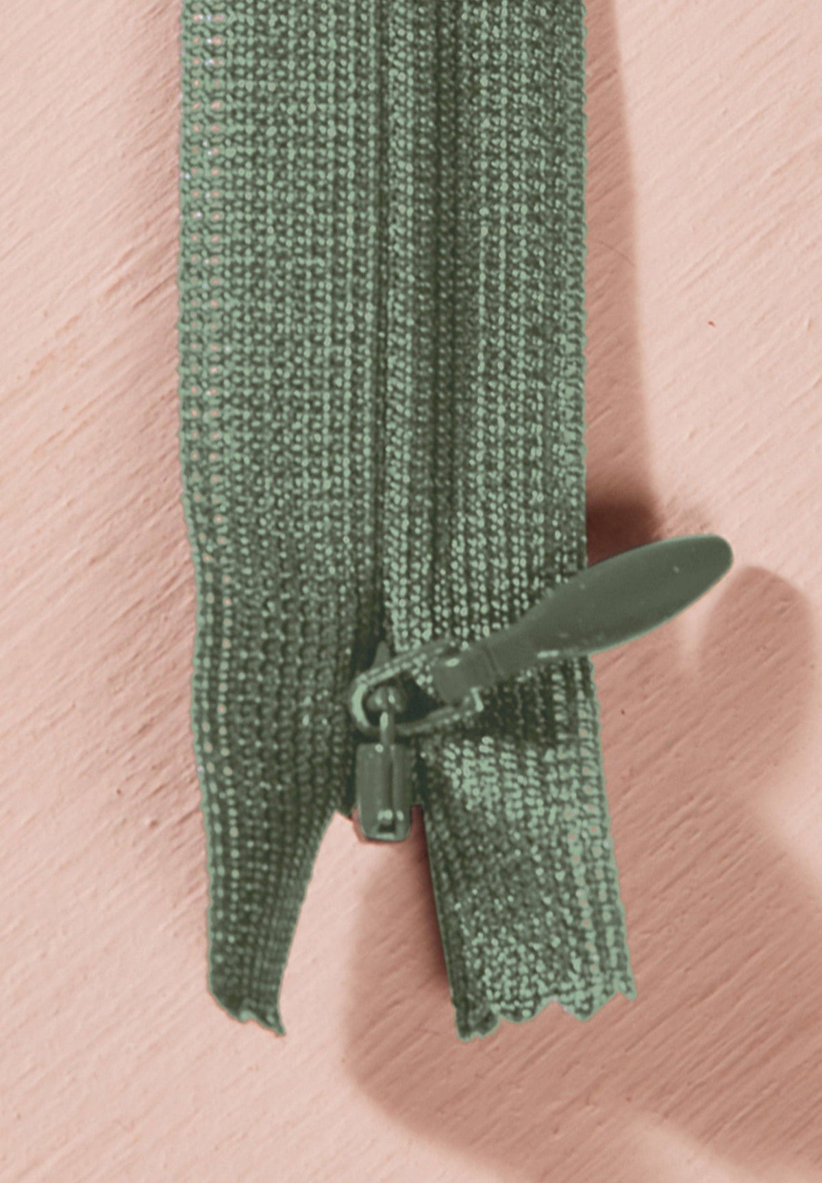 Atelier Brunette invisible zipper in sage green, vertical close-up, 40 cm (16 inch), a dressmaking notion for dresses and skirts shown on a blush background
