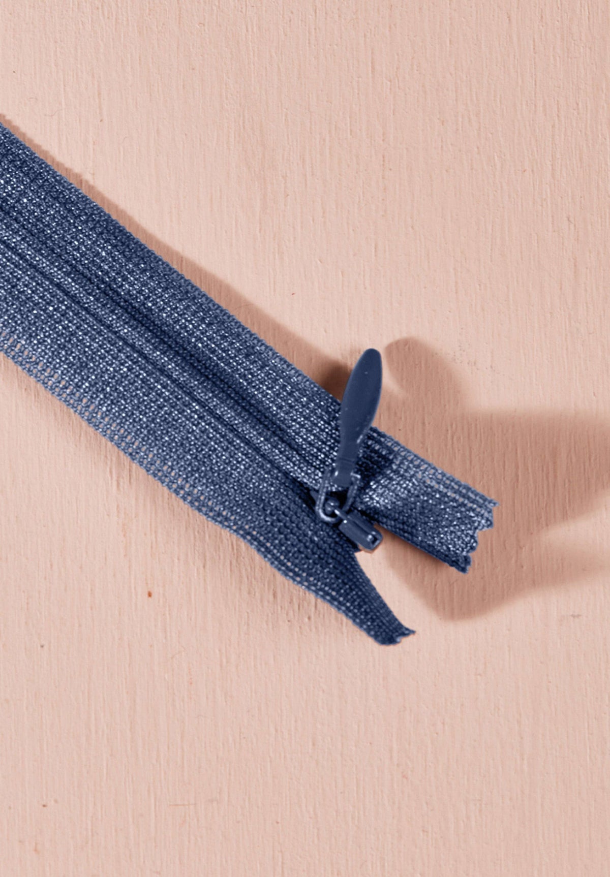 Atelier Brunette invisible zipper in cornflower blue, 40 cm (16 inch), a dressmaking notion for dresses and skirts shown on a blush background
