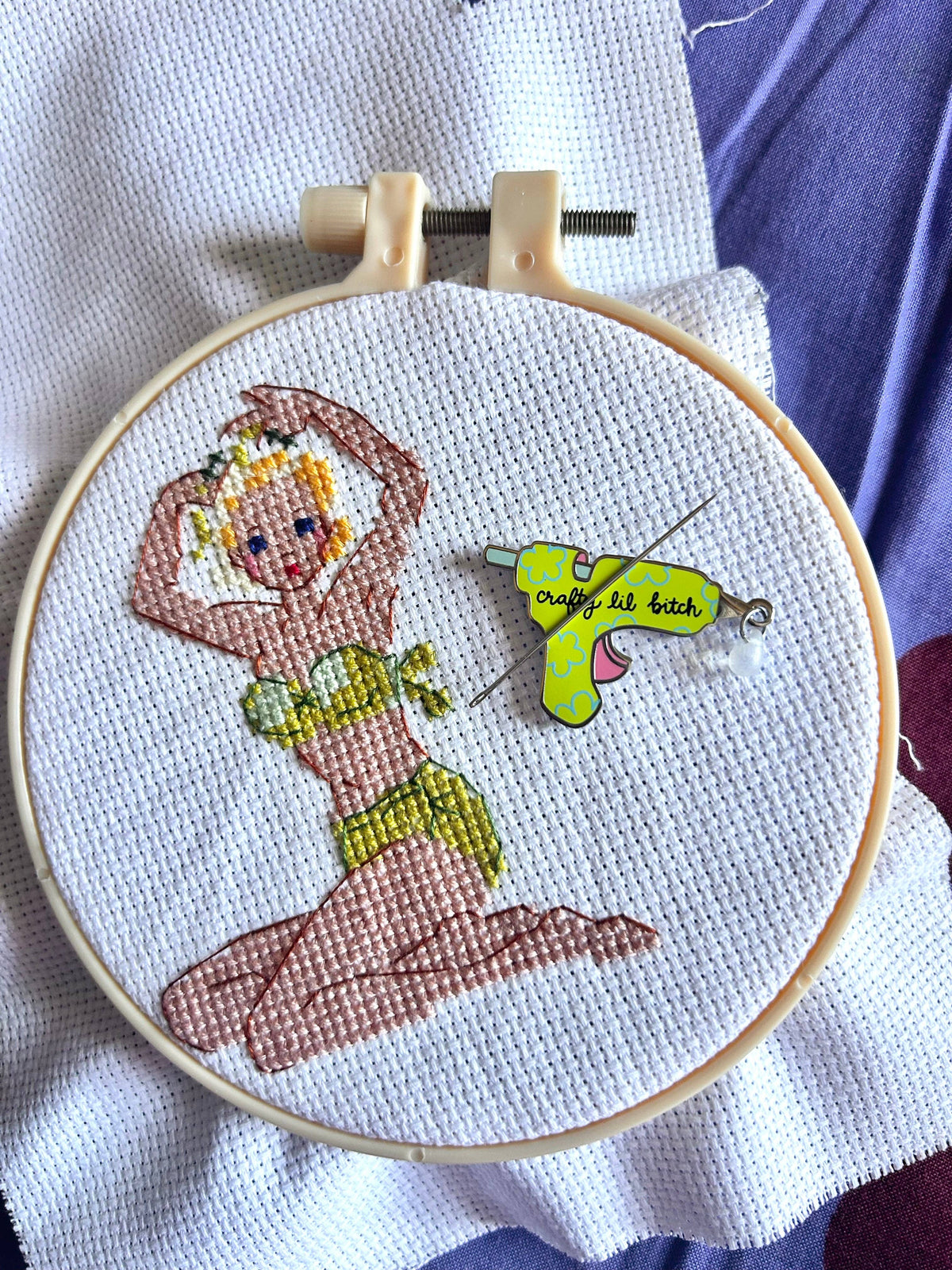 The Peach Fuzz Crafty Lil Bitch needle minder, a magnetic needle keeper on embroidery