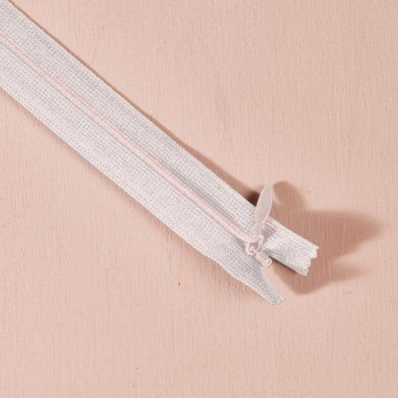 Atelier Brunette invisible zipper in white, 40 cm (16 inch), a dressmaking notion for dresses and skirts shown on a blush background