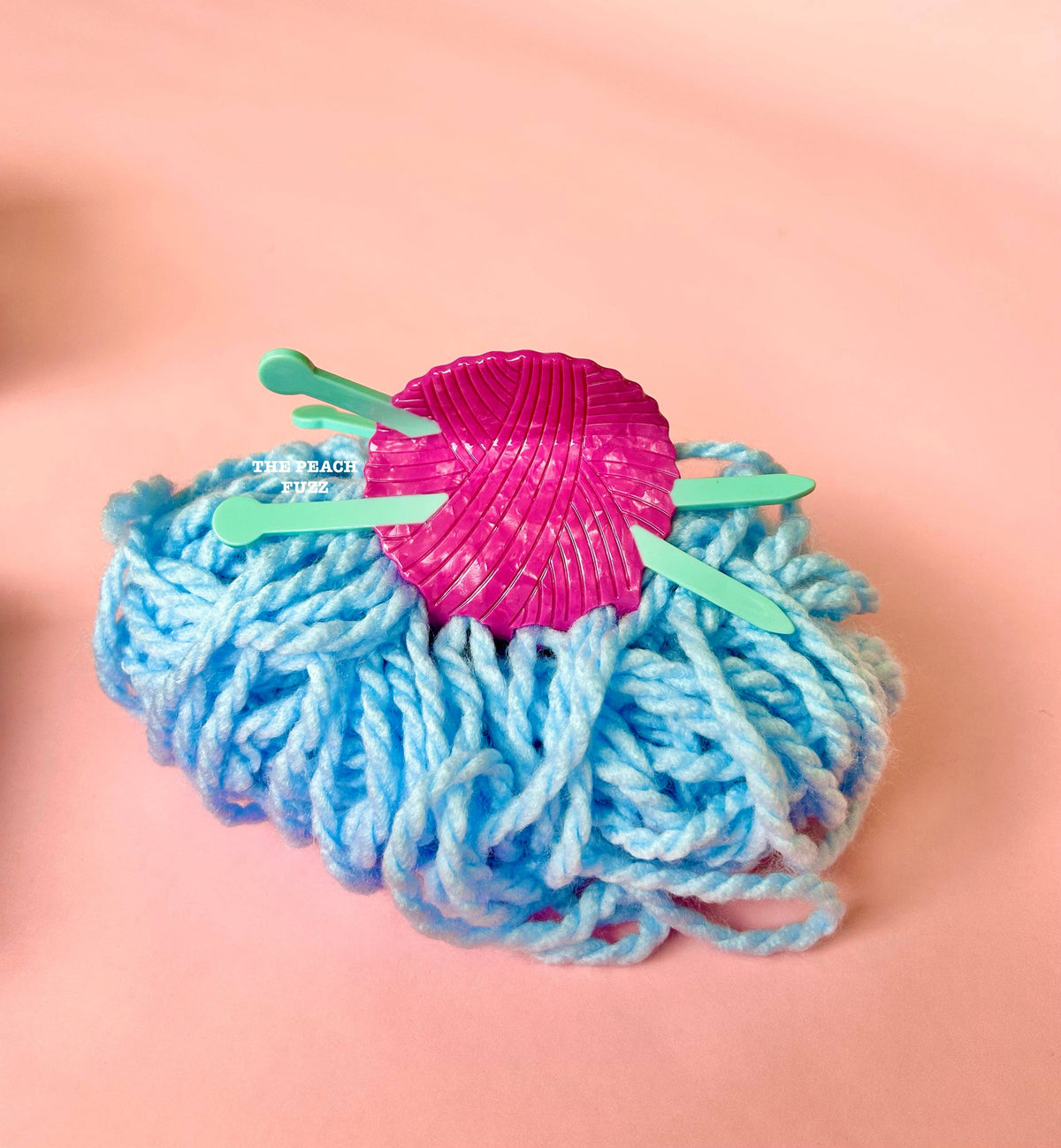 The Peach Fuzz knitting needle hair claw on blue yarn