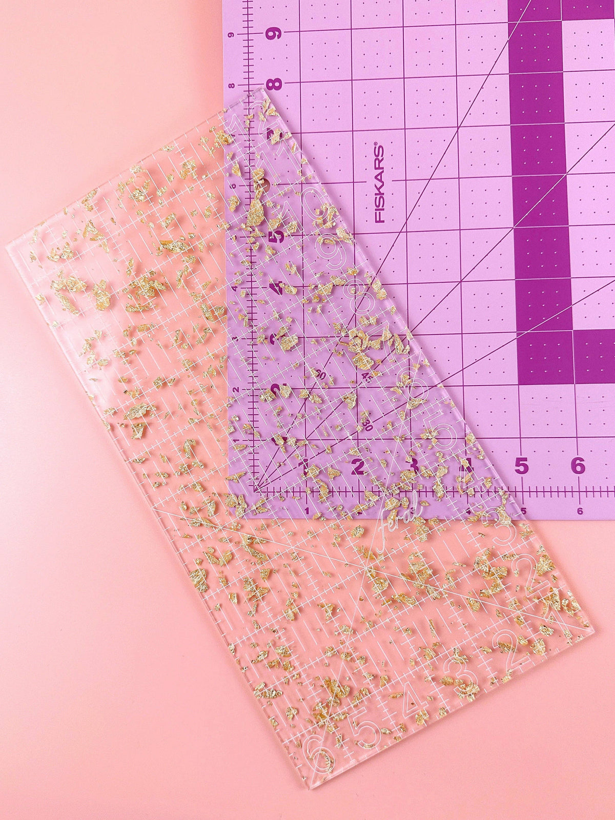 Feral Notions 6 x 12 inch quilting ruler in gold glitter acrylic on a pink cutting mat