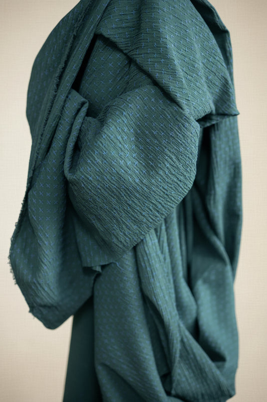 Dark blue textured fabric in a studio with cross stitched detailing 