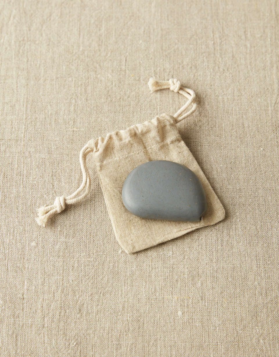 CocoKnits tape measure in Storm, a grey stone shaped retractable sewing and knitting tape, with its cotton drawstring pouch