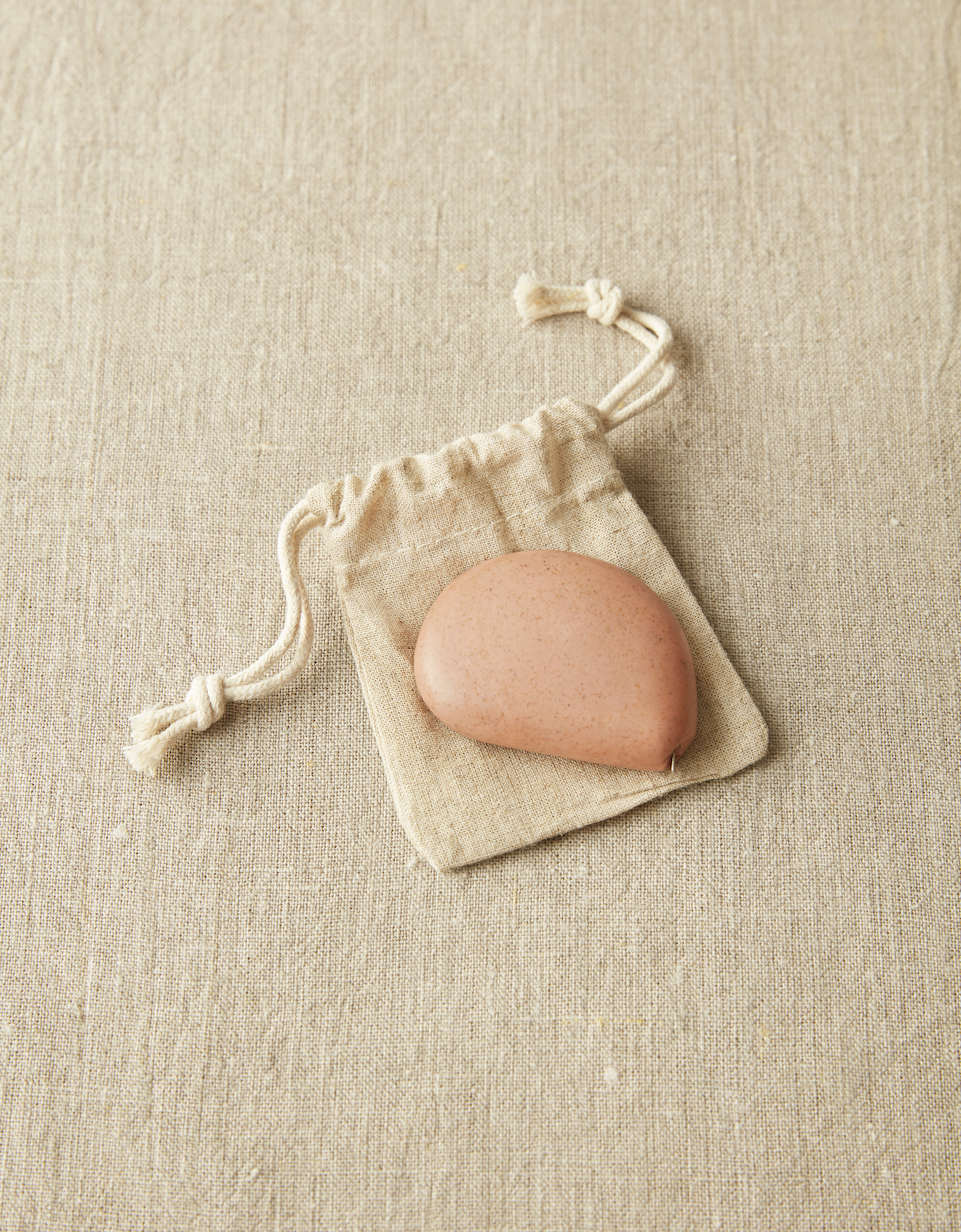 CocoKnits tape measure in Clay, a terracotta stone shaped retractable sewing and knitting tape, with its cotton drawstring pouch