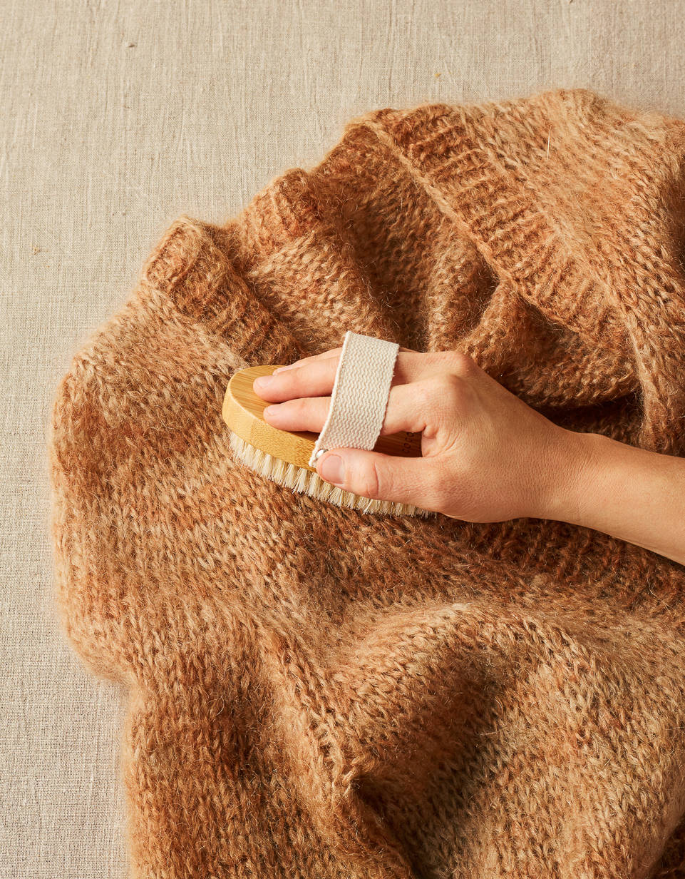 CocoKnits sweater care brush removing pills from a brown knit sweater