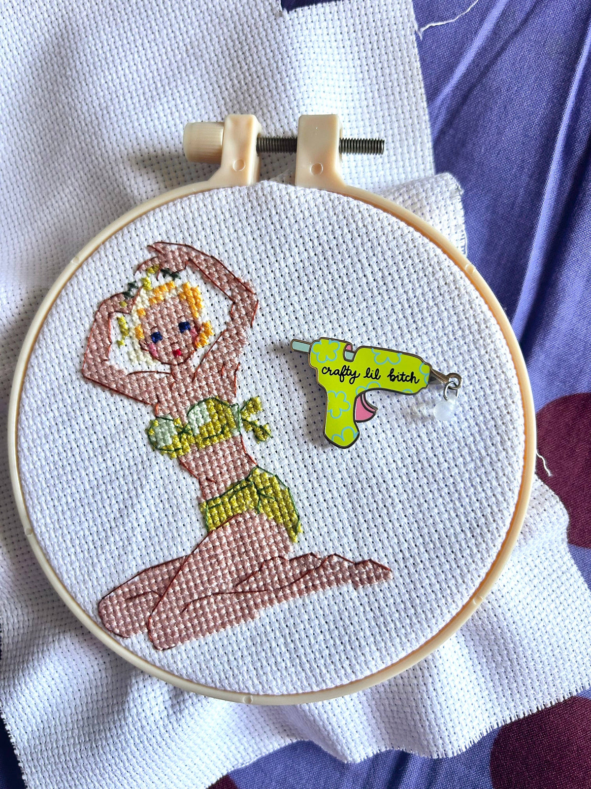 The Peach Fuzz Crafty Lil Bitch needle minder holding a needle on stitched fabric