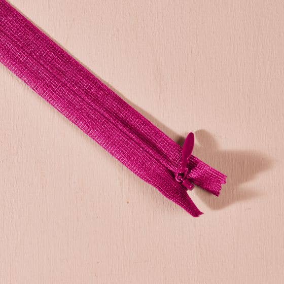 Atelier Brunette invisible zipper in dahlia magenta, 60 cm (24 inch), a dressmaking notion for dresses and skirts shown on a blush background