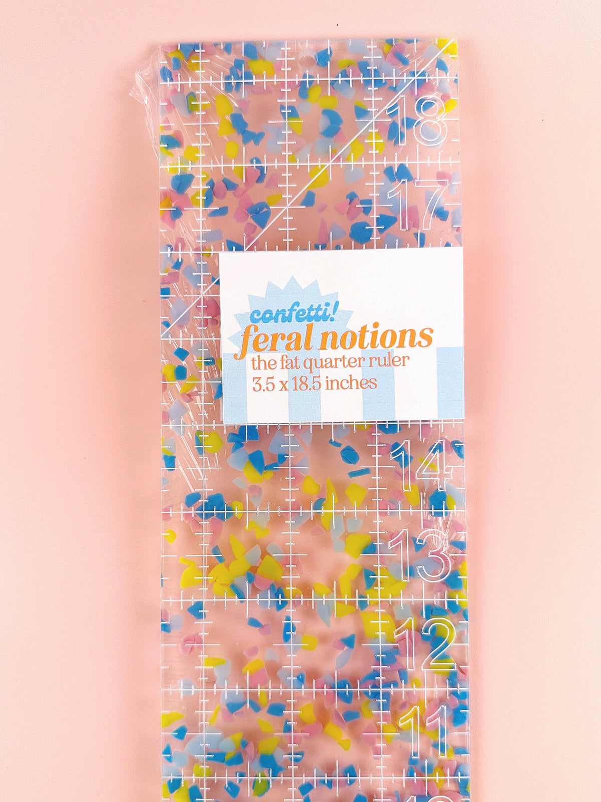 Feral Notions fat quarter quilting ruler in confetti acrylic with its paper label, a colorful quilting tool