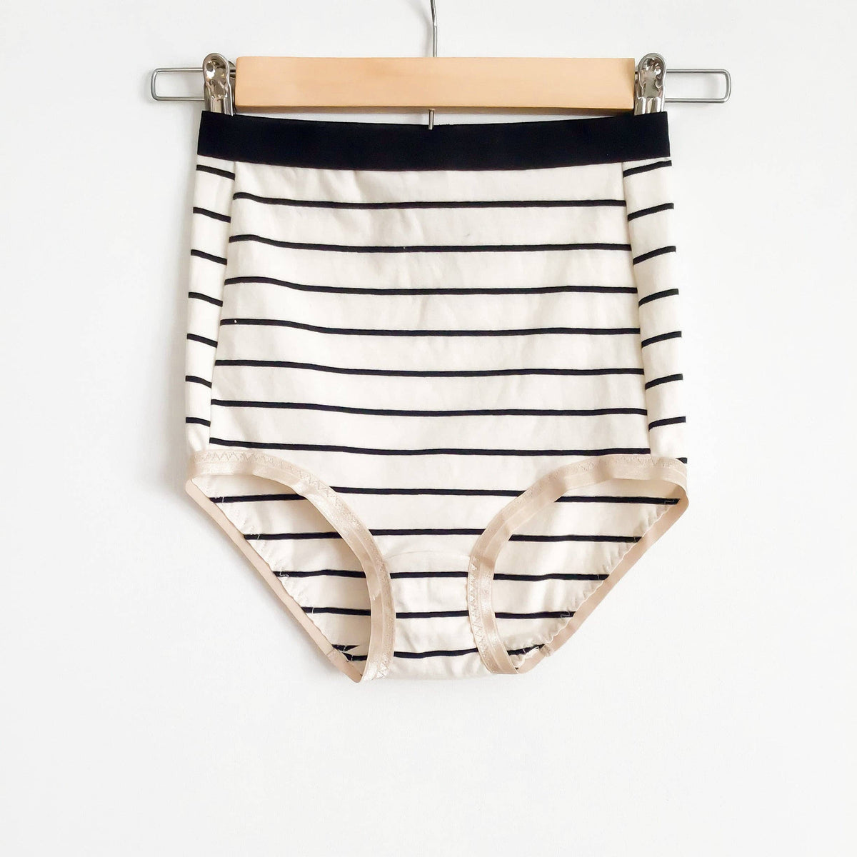 Striped knit knickers sewn from the Sophie Hines Median Knickers sewing pattern hanging on a wooden hanger