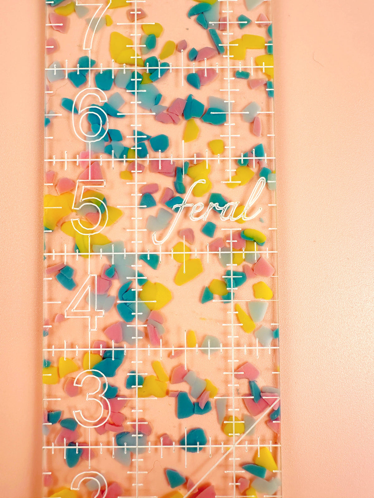 Close-up of the Feral Notions 2.5 x 10 inch quilting ruler in confetti acrylic showing the colorful speckles
