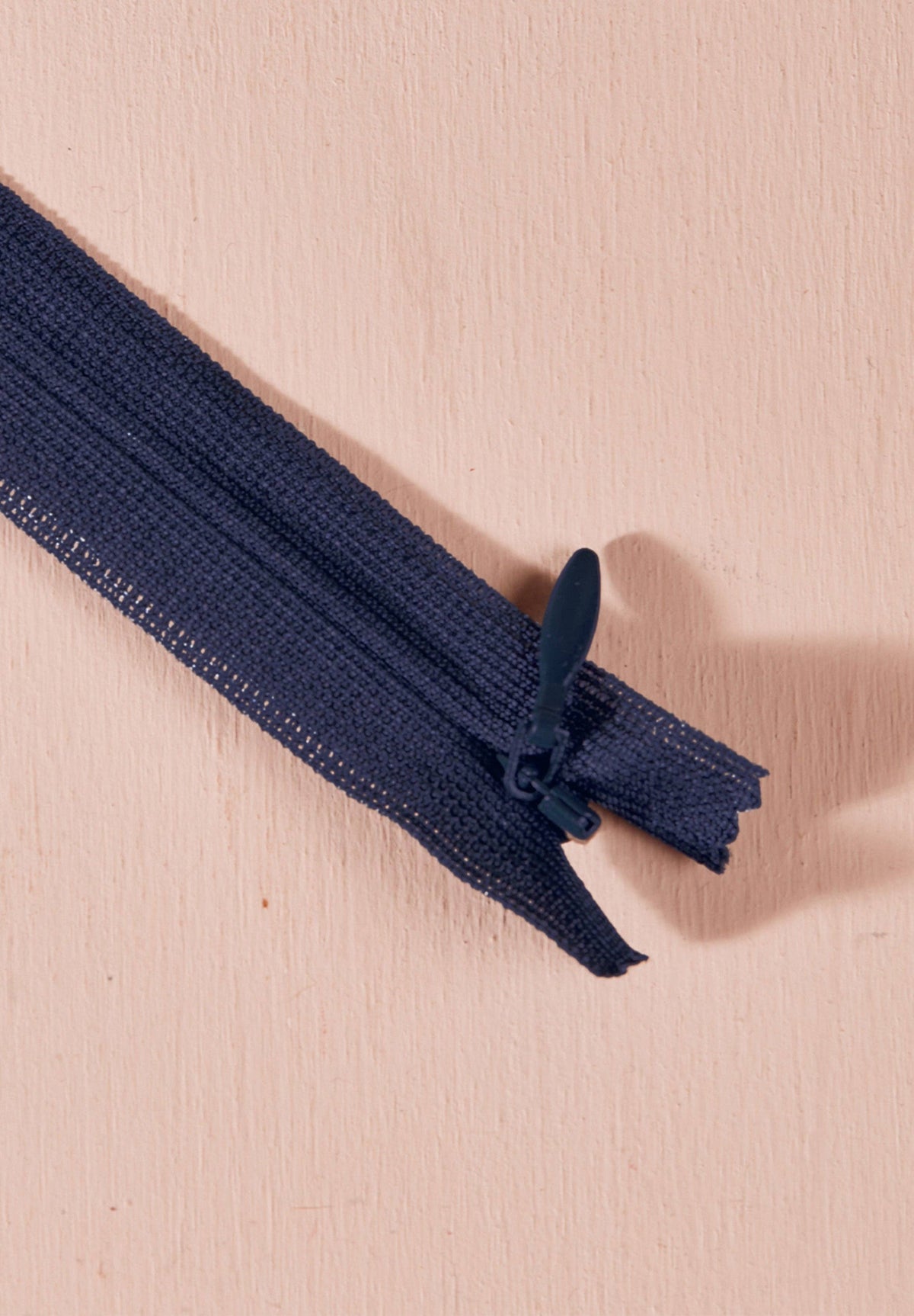 Atelier Brunette invisible zipper in navy, 40 cm (16 inch), a dressmaking notion for dresses and skirts shown on a blush background