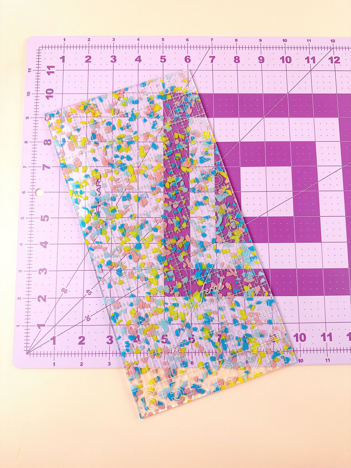 Feral Notions 6 x 12 inch quilting ruler in confetti acrylic laid on a lilac self-healing cutting mat