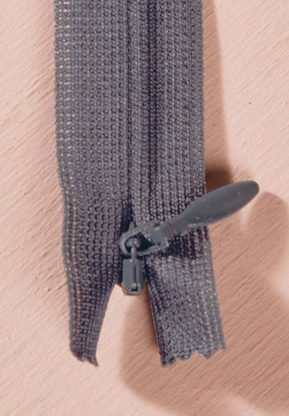 Atelier Brunette invisible zipper in charcoal grey, vertical close-up, 40 cm (16 inch), a dressmaking notion for dresses and skirts shown on a blush background