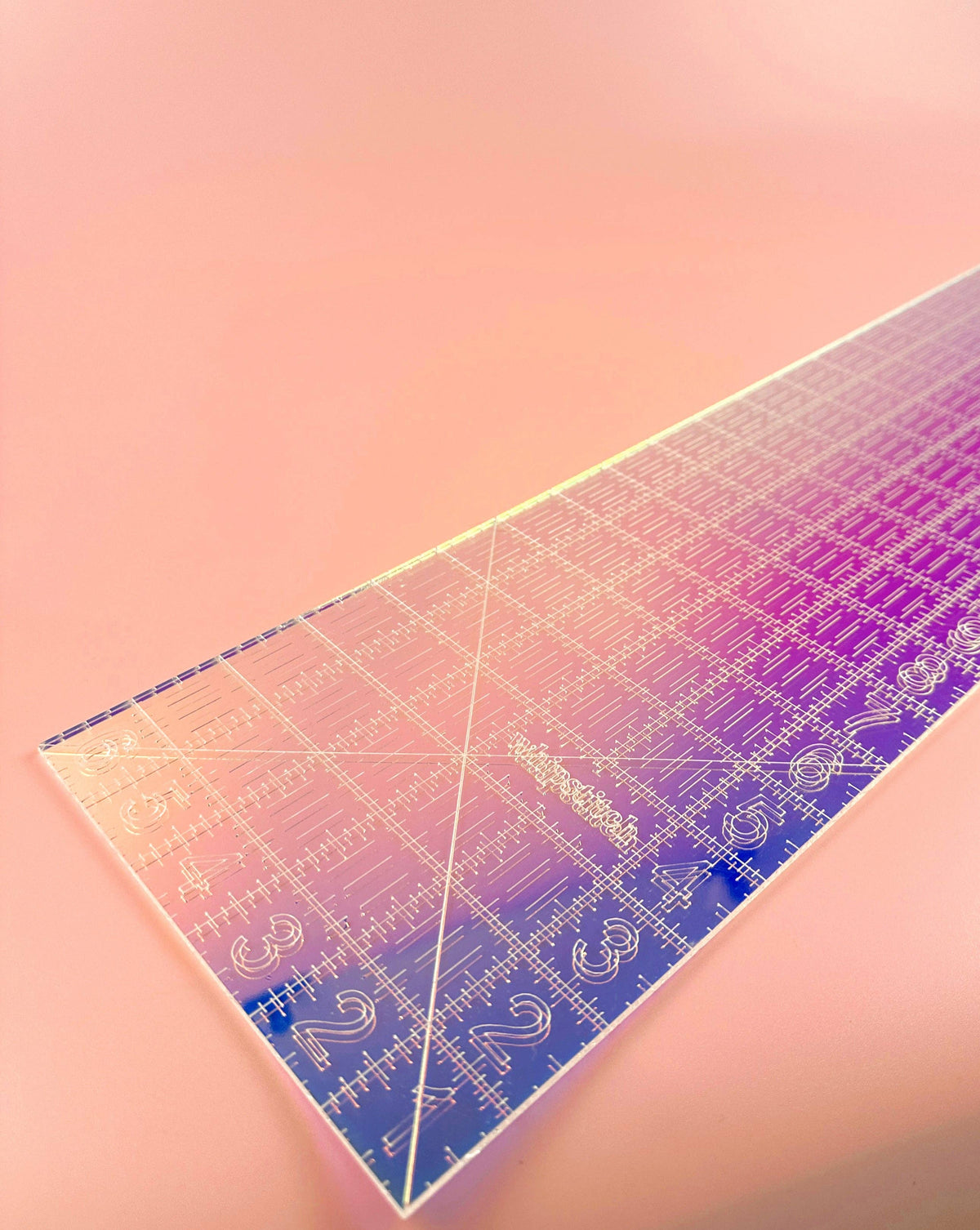 Feral Notions fat quarter quilting ruler in clear iridescent acrylic laid flat on peach