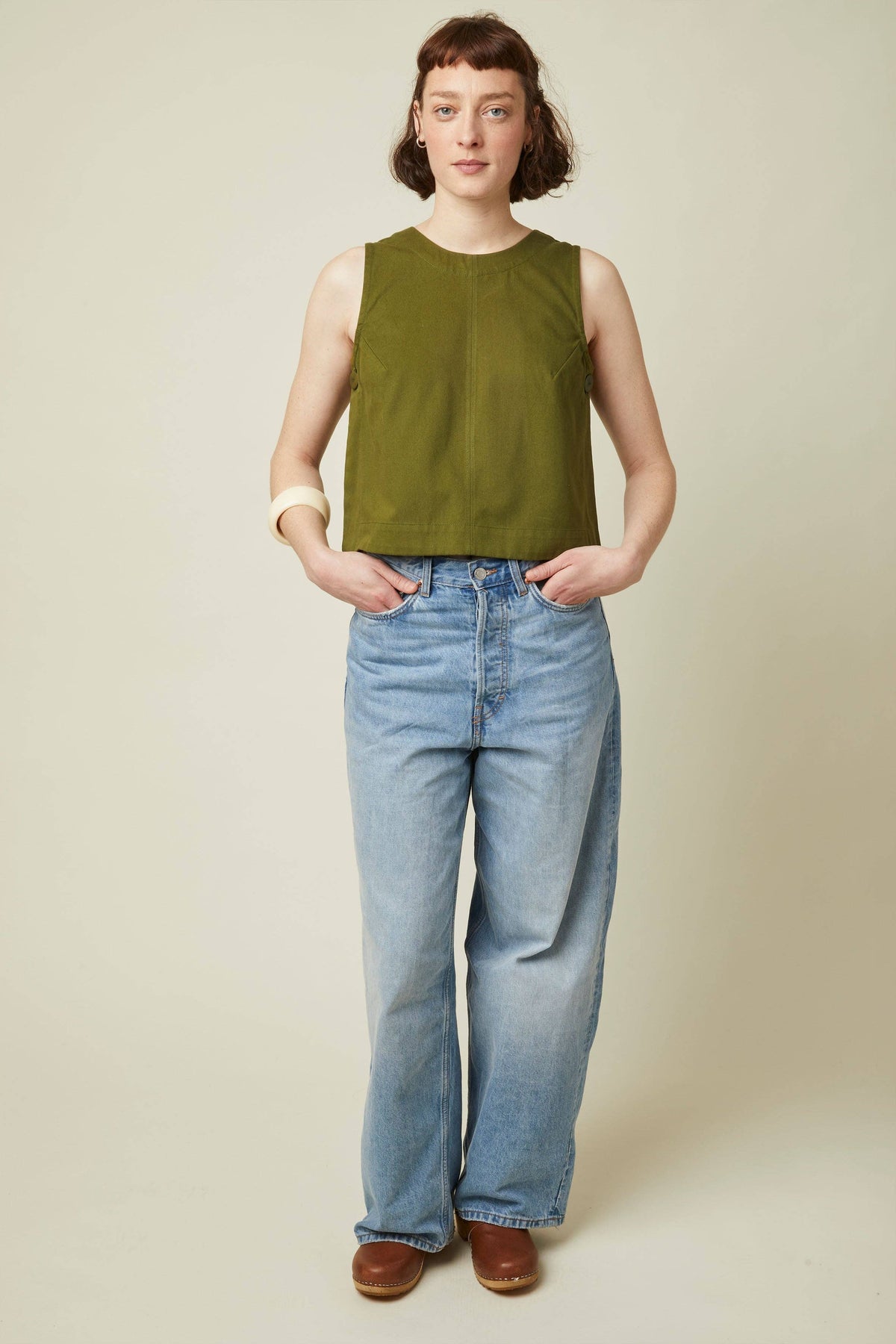 Model in an olive sleeveless top and jeans sewn from the Atelier Brunette The Top printed sewing pattern