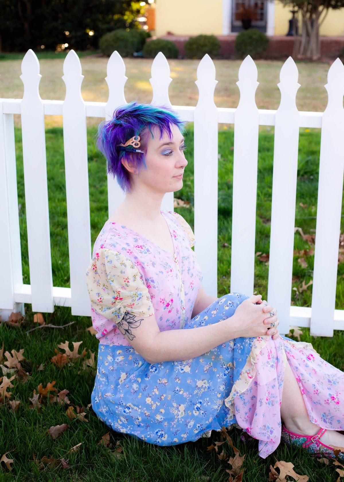 Model in a floral dress wearing The Peach Fuzz sewing kit hair clips by a picket fence