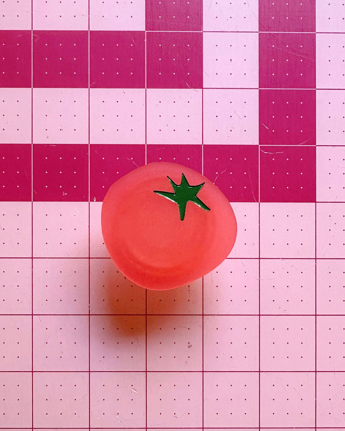 Feral Notions tomato pop-up ruler handle in red on a pink cutting mat