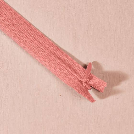 Atelier Brunette invisible zipper in coral pink, 40 cm (16 inch), a dressmaking notion for dresses and skirts shown on a blush background