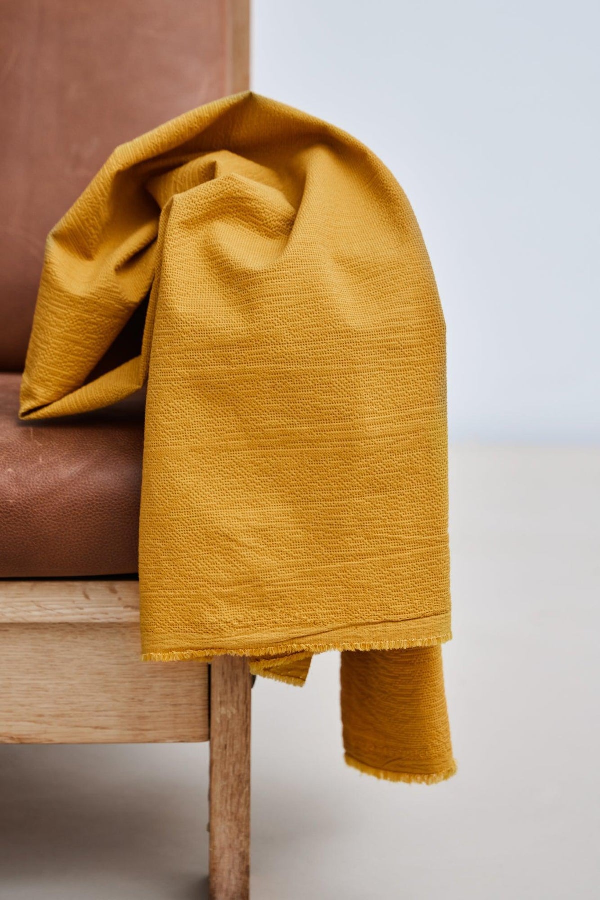 Picnic cotton blend seersucker in Amber, mustard textured apparel fabric by the half yard over a chair