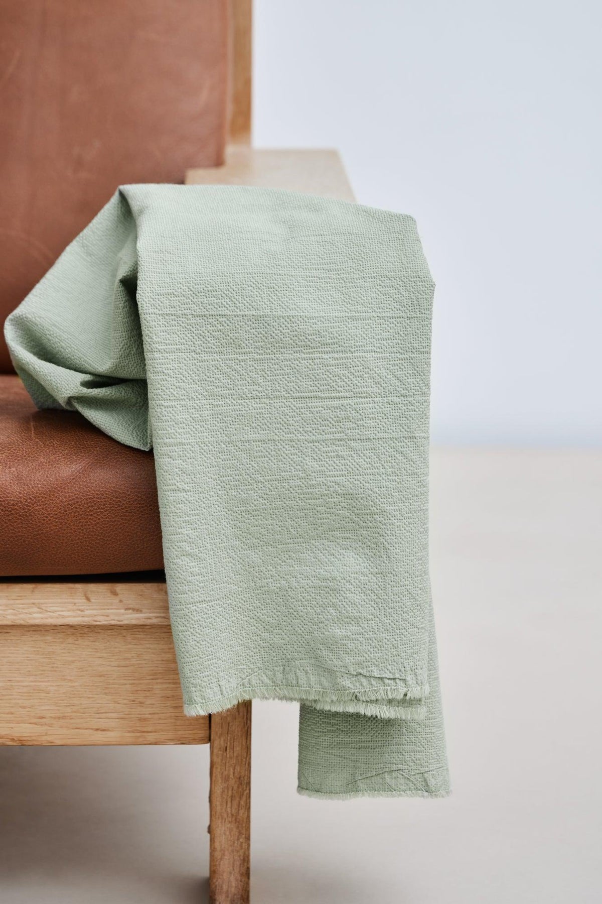 Picnic cotton blend seersucker in Soft Mint, pale green crinkle fabric by the half yard over a chair