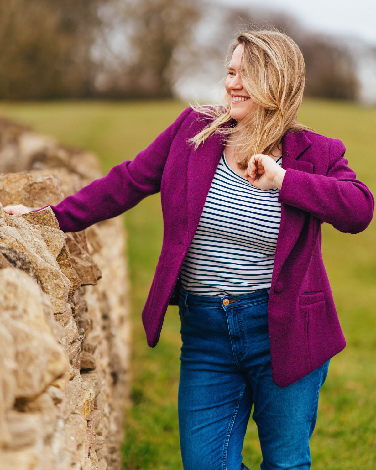 Cashmerette Auburn Blazer PDF sewing pattern, woman in a purple coat standing next to a stone wall in a field