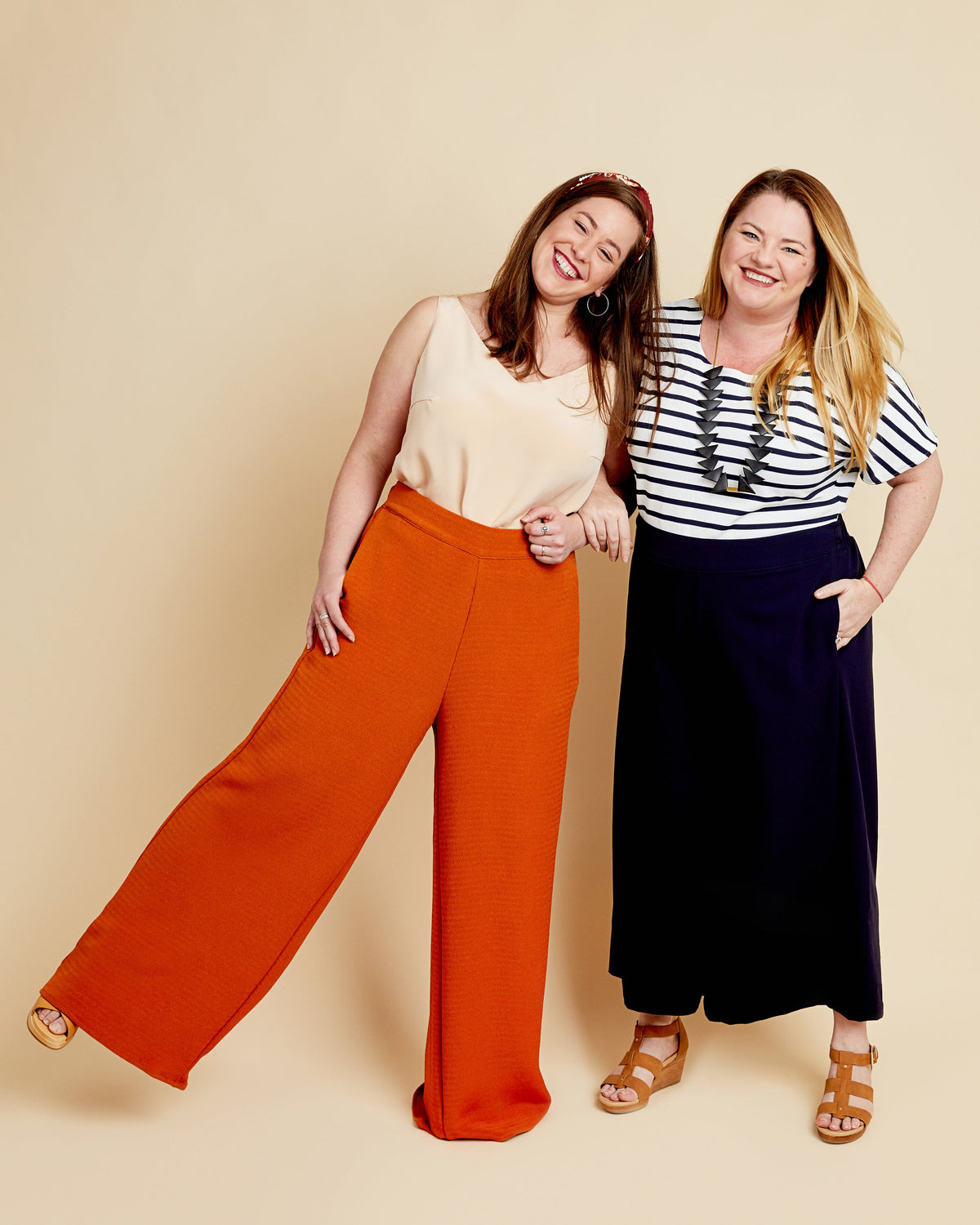Cashmerette Calder Pants and Shorts PDF sewing pattern, two women standing side by side, one wearing orange pants and a beige top, the other in a