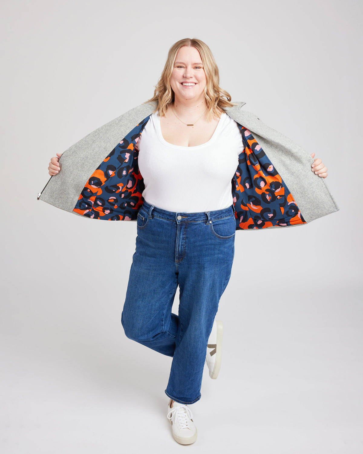 Cashmerette Canton Moto Jacket PDF sewing pattern, woman wearing a white top, blue jeans, and a colorful jacket over her shoulders