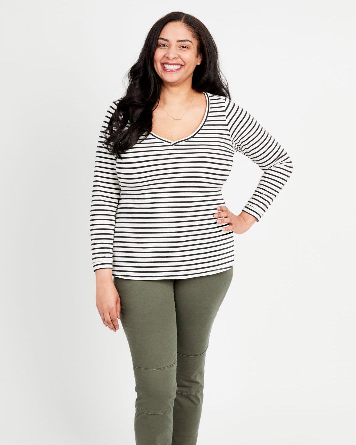 Cashmerette Concord T-Shirt PDF sewing pattern, woman standing, wearing a striped long-sleeved t-shirt and green pants