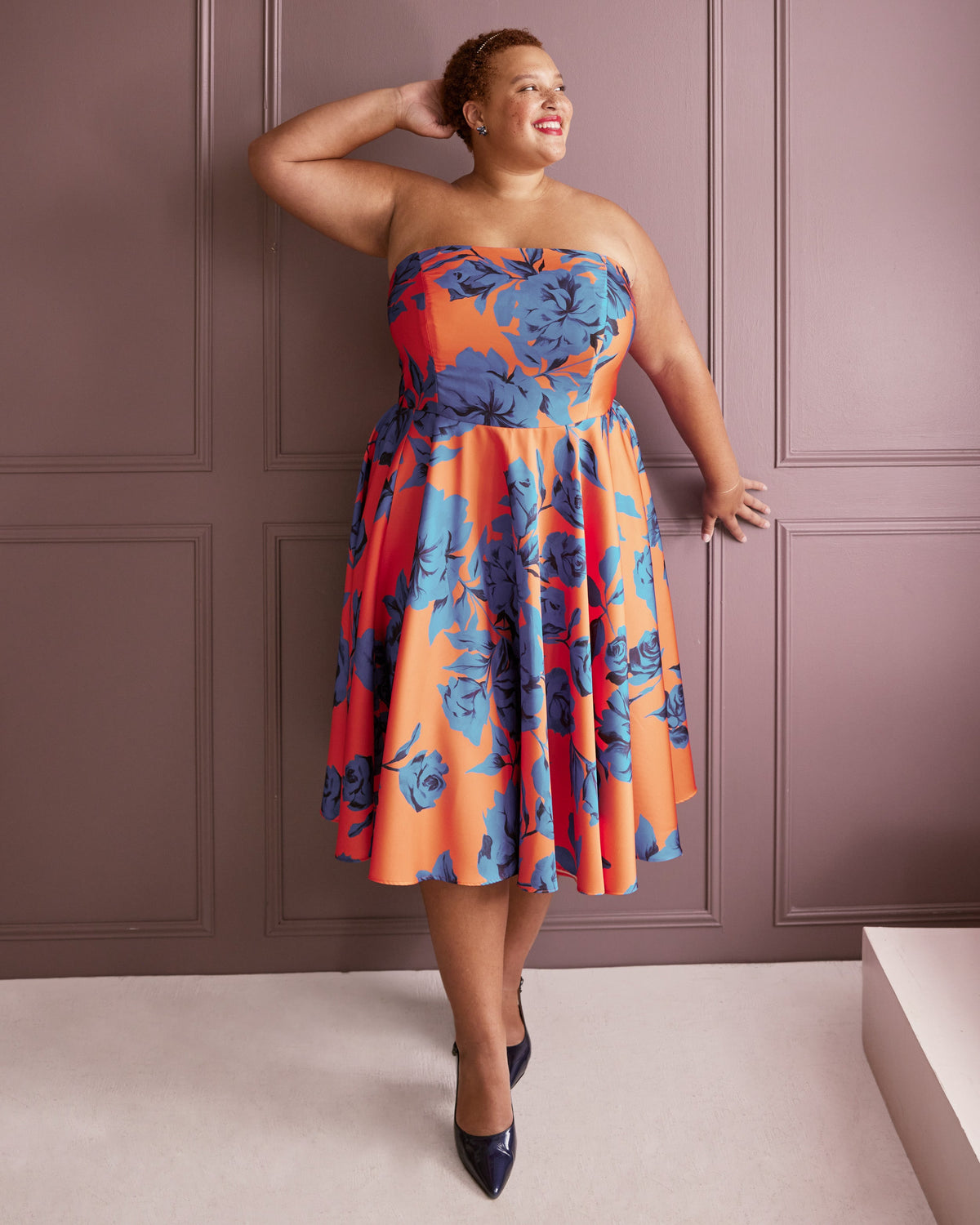 Cashmerette Ellington Dress PDF sewing pattern, woman wearing a strapless dress with blue floral pattern against a pink paneled wall