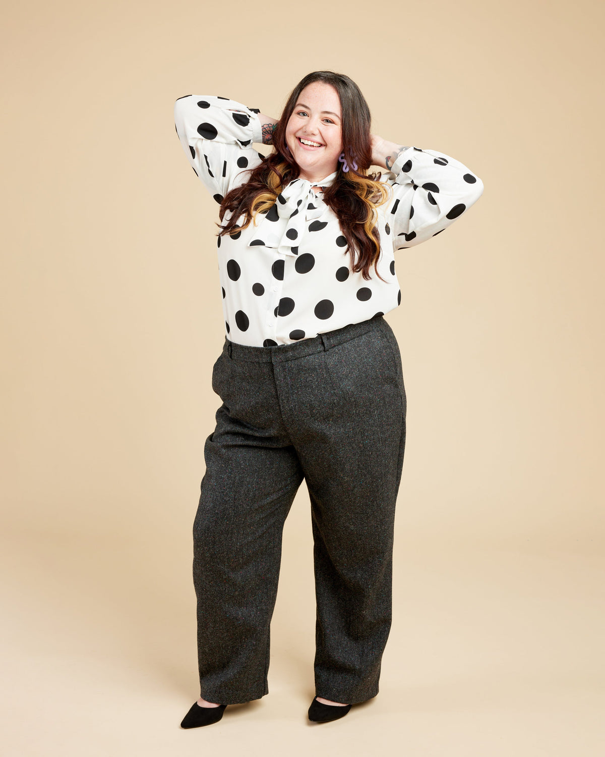 Cashmerette Meriam Trousers PDF sewing pattern, person wearing a polka dot blouse and gray pants, hand on hip