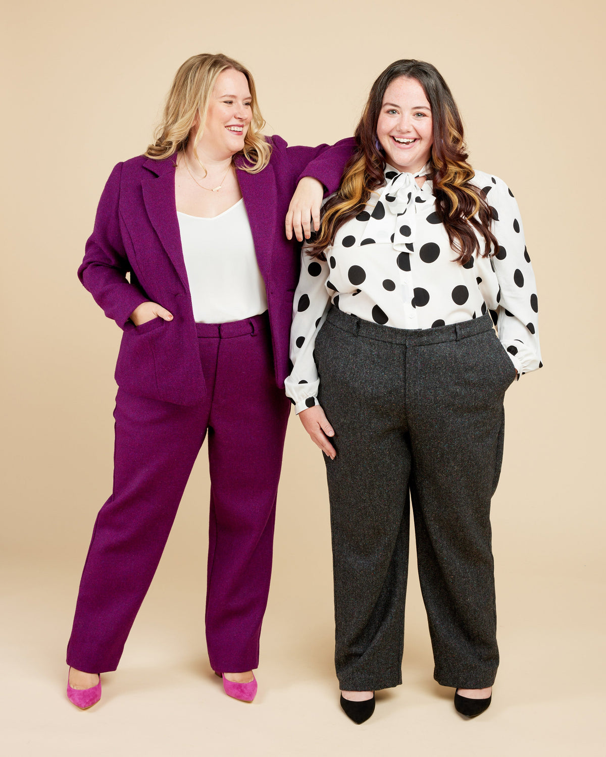 Cashmerette Meriam Trousers PDF sewing pattern, two women posing together, one in a purple suit and the other in a polka dot blouse and gray pants..