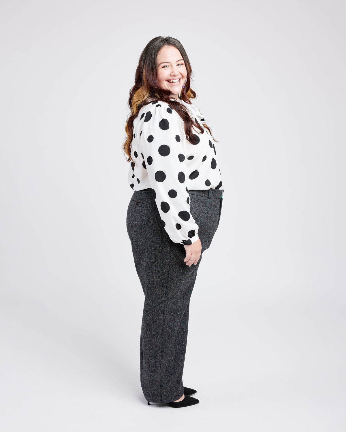 Cashmerette Meriam Trousers PDF sewing pattern, woman wearing a polka dot blouse and gray pants, side view