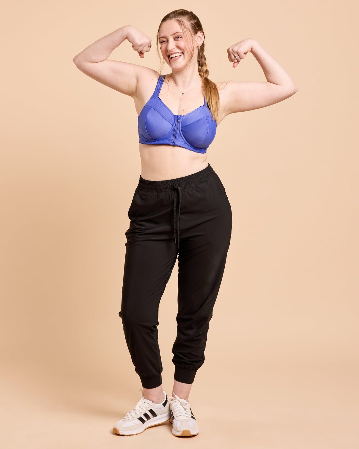 Cashmerette Somerville Sports Bra PDF sewing pattern, woman flexing her muscles wearing a blue sports bra and black jogger pants